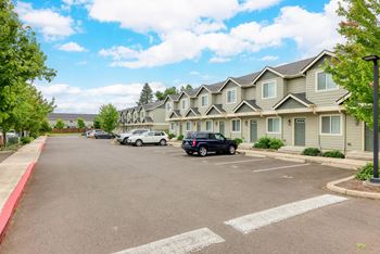 a parking lot with cars parked in front of apartment buildings at Trillium Apartments, Springfield, OR